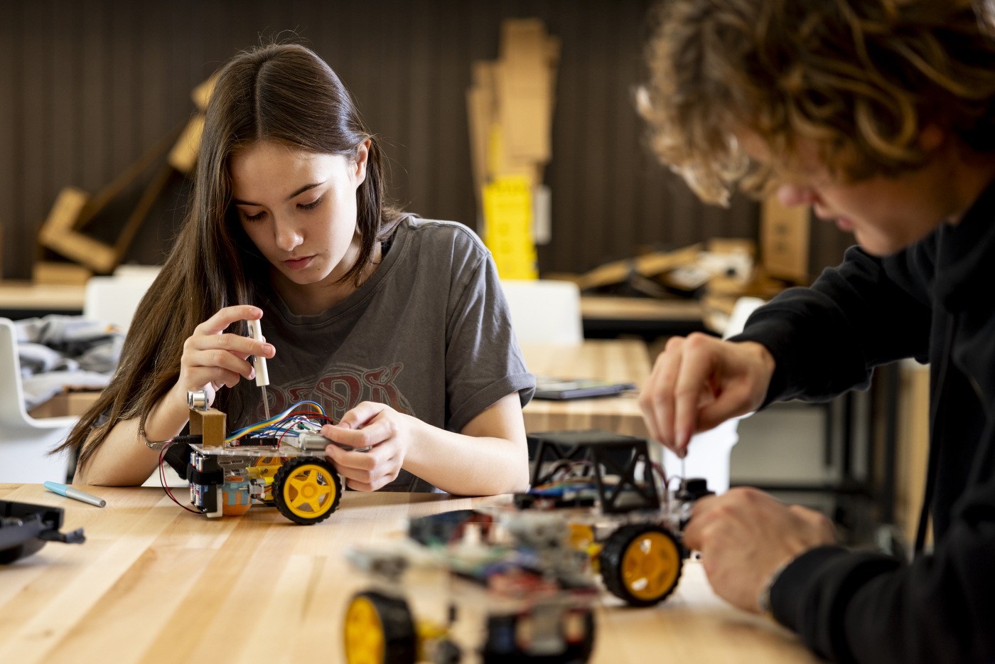 Students working on a self-driving robot at a table.