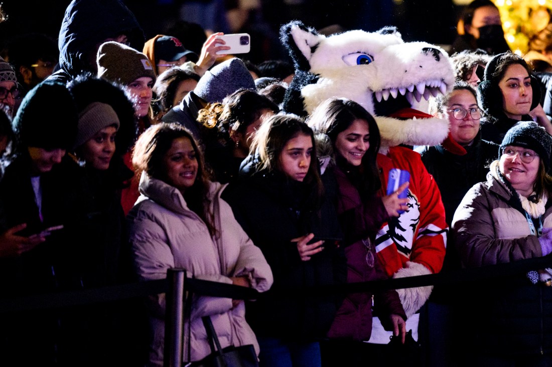 People stand outside with Northeastern's mascot Paws during Northeastern's Joy and Light Holiday Showcase.