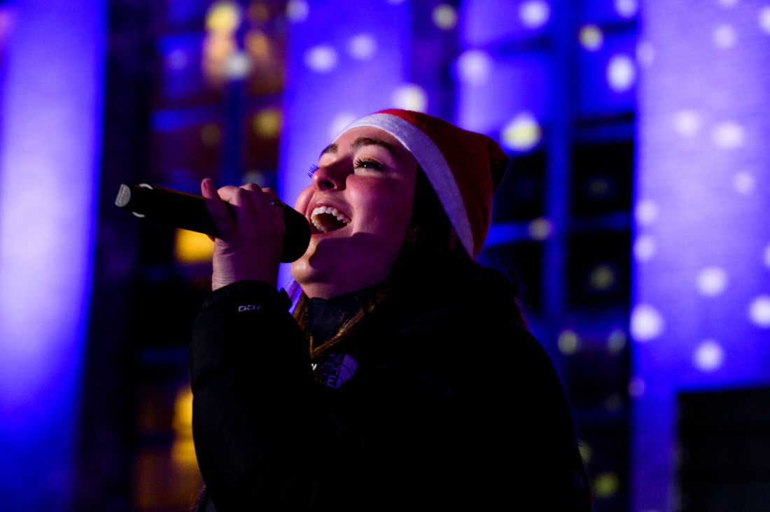 A person sings into a microphone at Northeastern's holiday celebration.