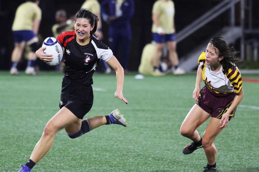 Northeastern womens rugby player running on the field with the ball. 