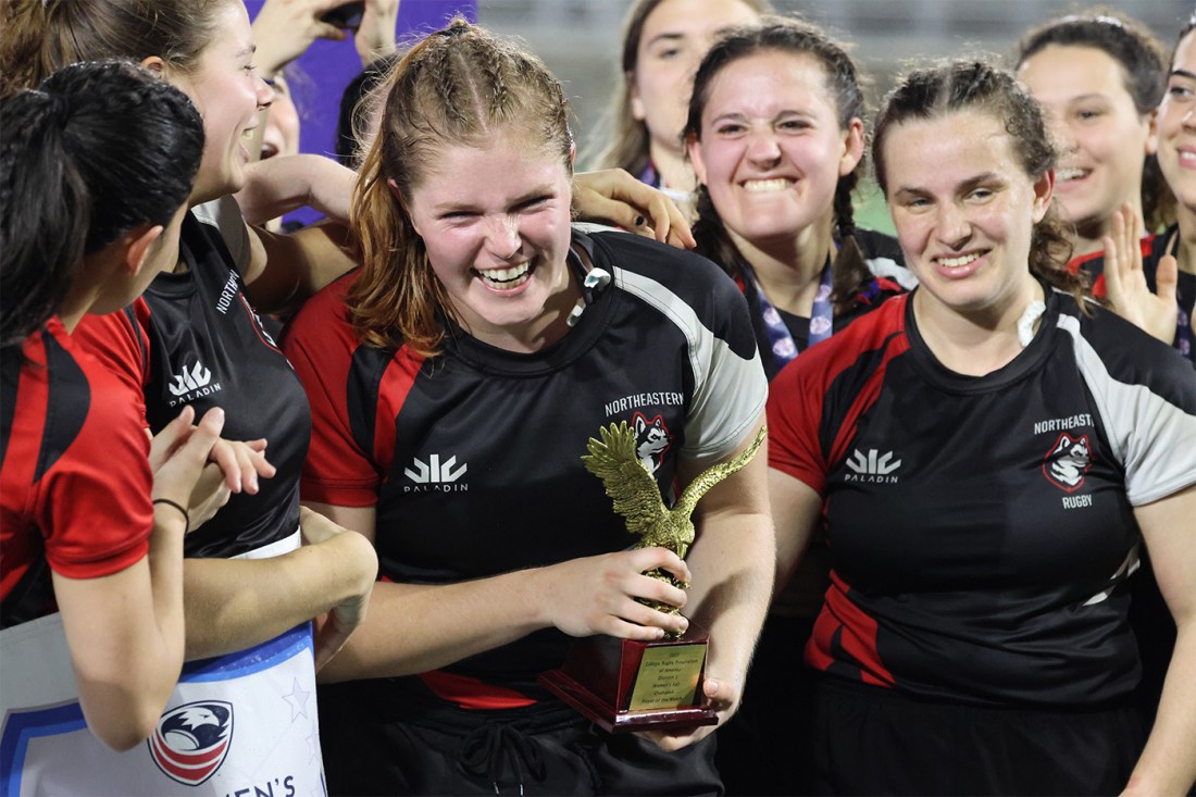 Northeastern women's rugby players holding a trophy.