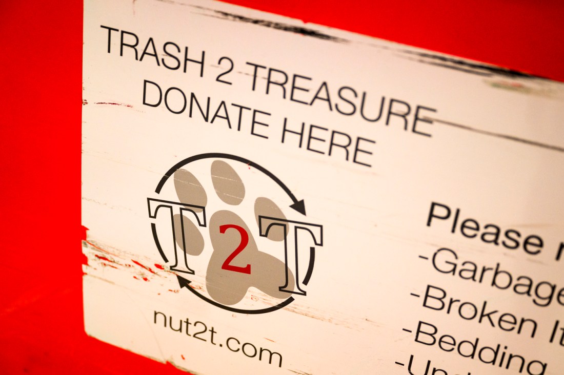 A red Trash 2 Treasure donation box with the T2T logo over top of a paw print on it. 