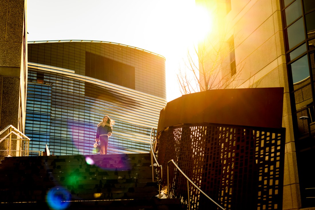 Northeastern community member descending the stairs from the bridge between ISEC and EXP during golden hour. 