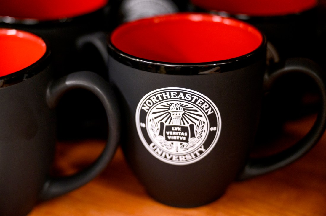 A black mug with a red inside and the university seal in white.