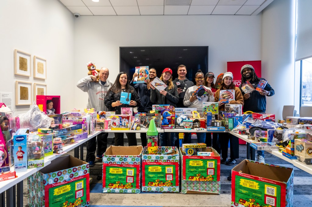 City and Community Engagement Staff members pose with tables full of toy donations.