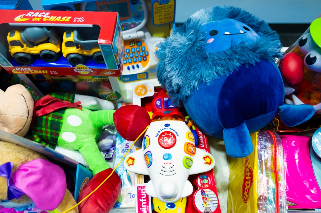 Toys piled on top of each other including a yellow toy truck and a stuffed blue monster.