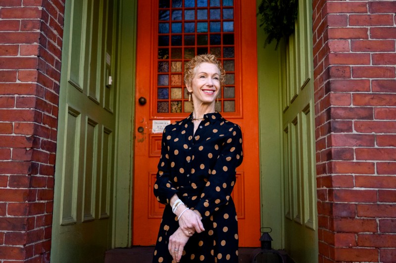 Amy Dablemont Burnes posing in front of a building with a red door. 