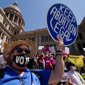 Abortion rights demonstrators outside of the Texas state capitol, one carrying a blue circular sign that says 'keep abortion legal' on it in white text