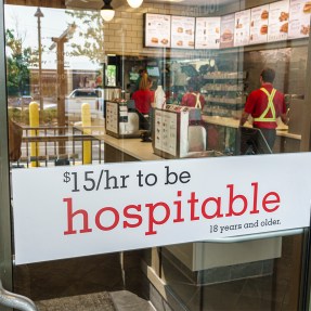 A sign on a Chick-fil-A door that says "$15/hr to be hospitable".