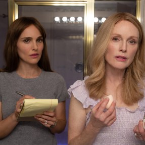 Screen capture from the film May December of Julianne Moore and Natalie Portman both standing looking in a mirror while doing their makeup.