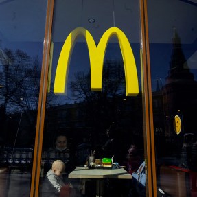 People eating in a McDonalds restaurant under the yellow M logo.