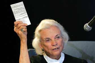 Sandra Day O'Connor holding up a copy of the US Constitution.