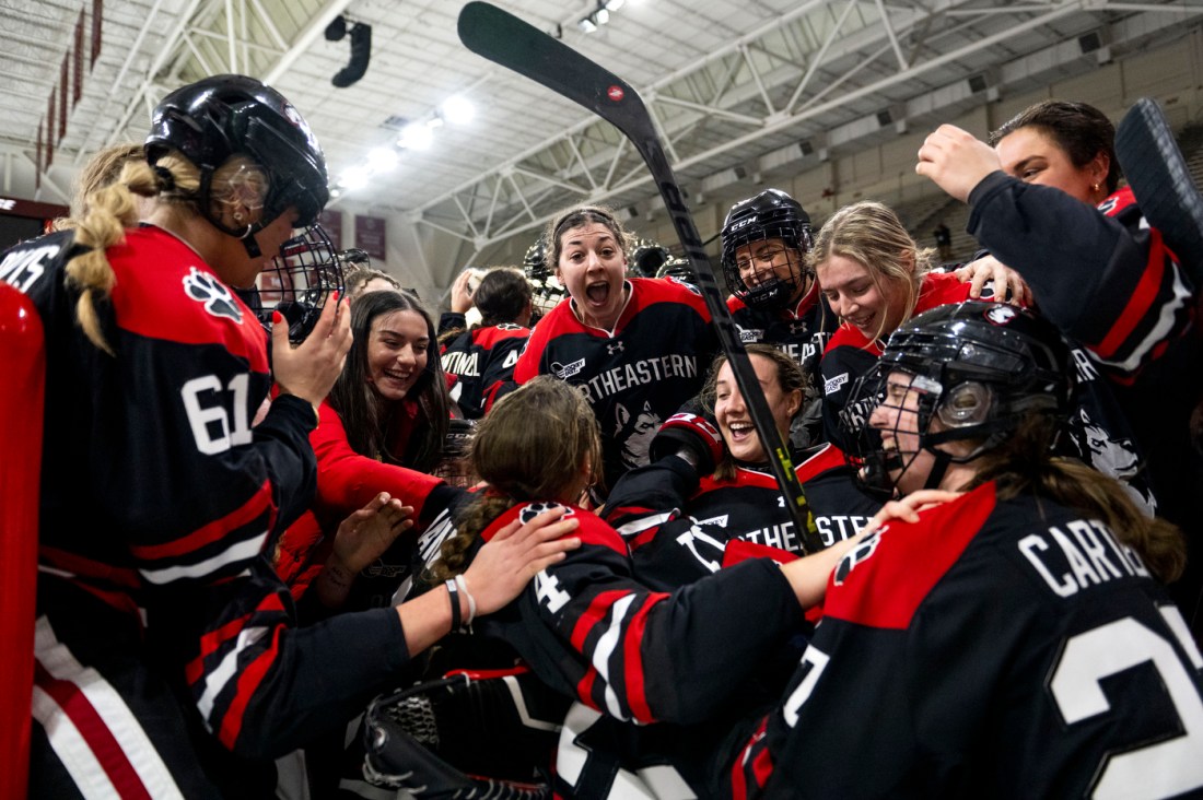 Members of the women's hockey team jumping on each other and cheering.