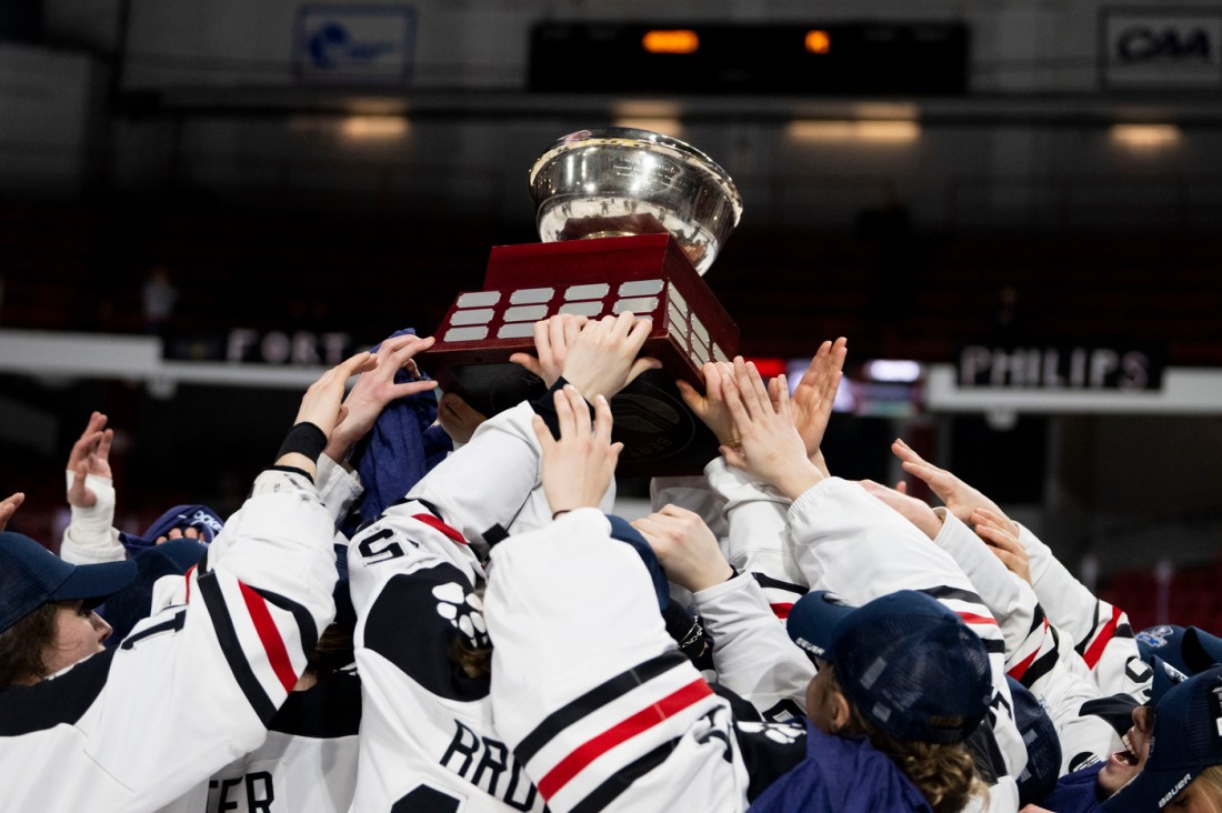 Northeastern hockey team members lifting the beanpot trophy.