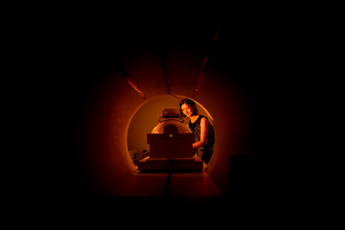 Person entering an MRI tube in orange lighting.