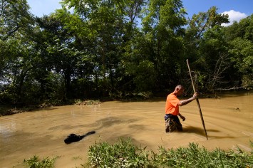 Dustin Shadownes walking in a creek with a cadaver dog.
