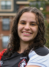 Headshot of Hannah Wilker outside in their Rugby uniform.