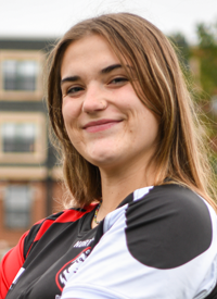 Headshot of Kyra Grimes outside in their Rugby uniform.