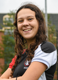 Headshot of Madi Singlak outside in their Rugby uniform.