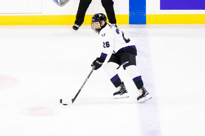 A womens hockey player skating on ice.