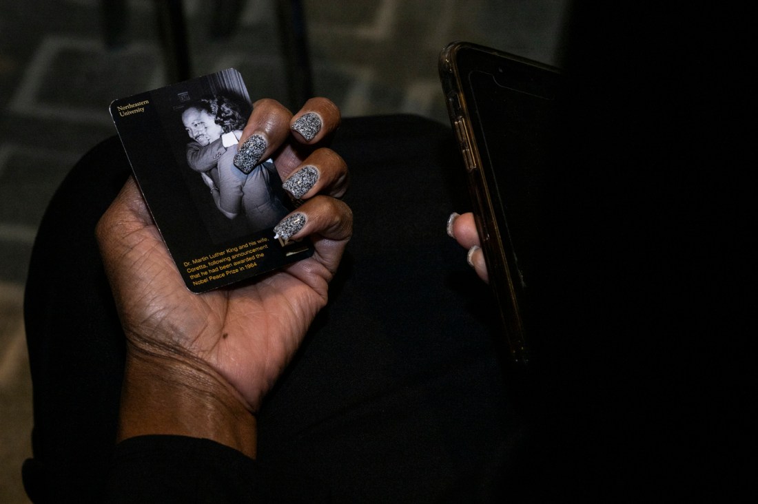 A closeup of a hand holding a small card printed with Martin Luther King Jr. and 
Coretta Scott King's pictures and names.