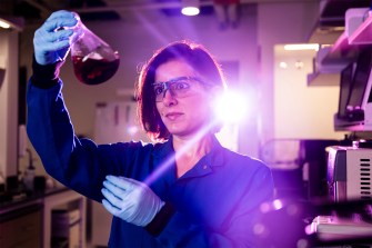 Leila Deravi inspects a beaker in her lab within the EXP research complex on the Boston campus.