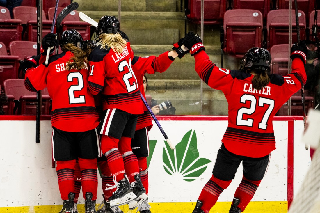 Multiple Northeastern hockey players cheer after winning at the Women's Beanpot Semifinal.