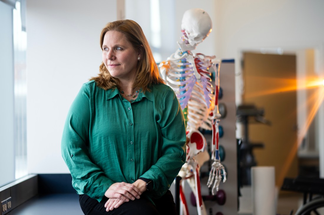 Dr. Maureen Watkins posing for a headshot in front of an instructional skeleton.