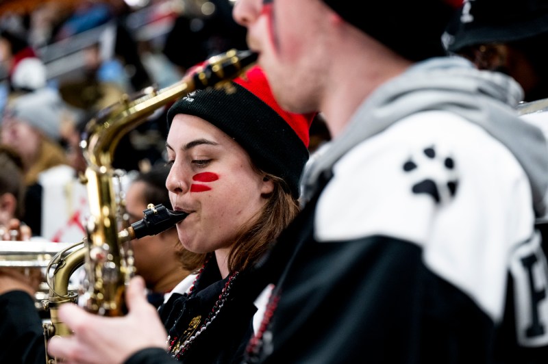 Two members of the Northeastern band with face paint on their face playing saxophones.