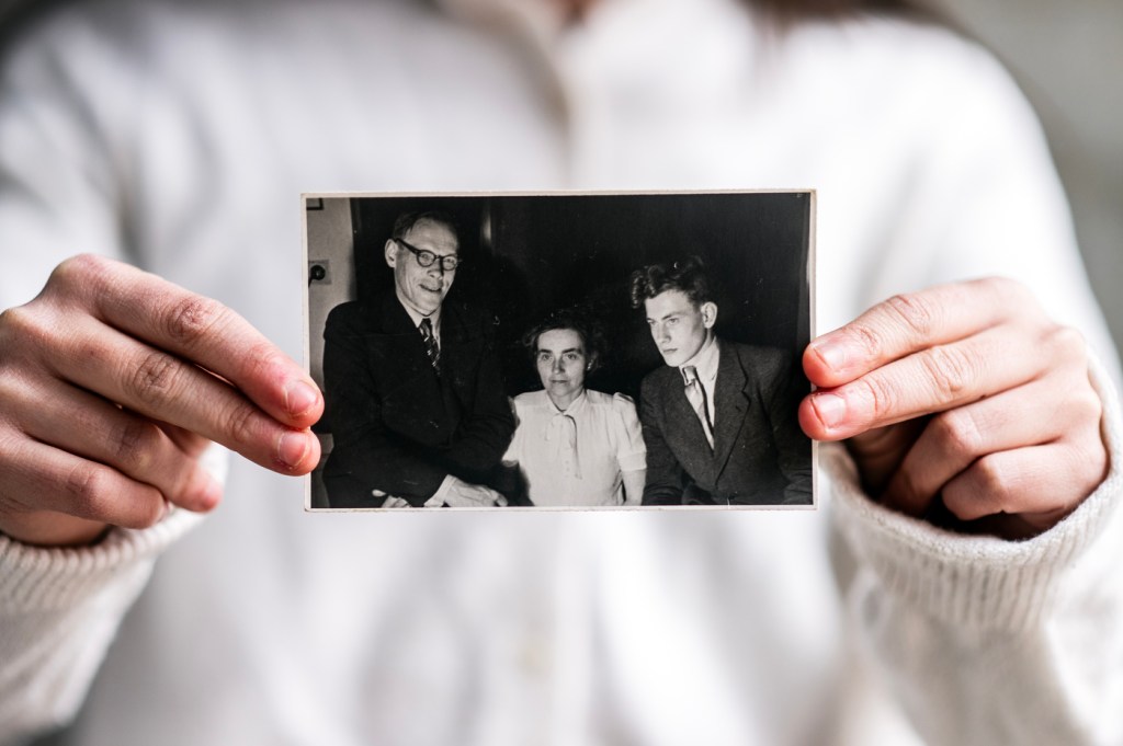 Andie Weiner holding a black and white photograph of the Dutch family members who hid her grandfather from the Nazis.