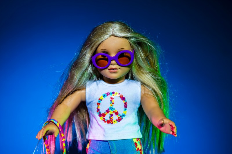 The Julie American Girl doll wearing a white shirt with a peace symbol and purple sunglasses.