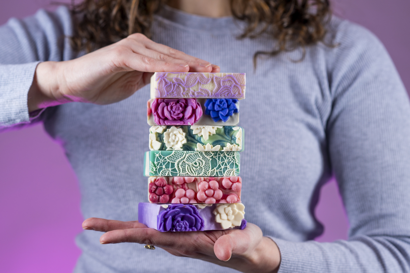 Tori Farley holding a stack of handmade soaps.