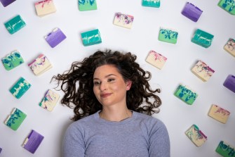 Tori Farley posing by laying on the ground surrounded by soaps.