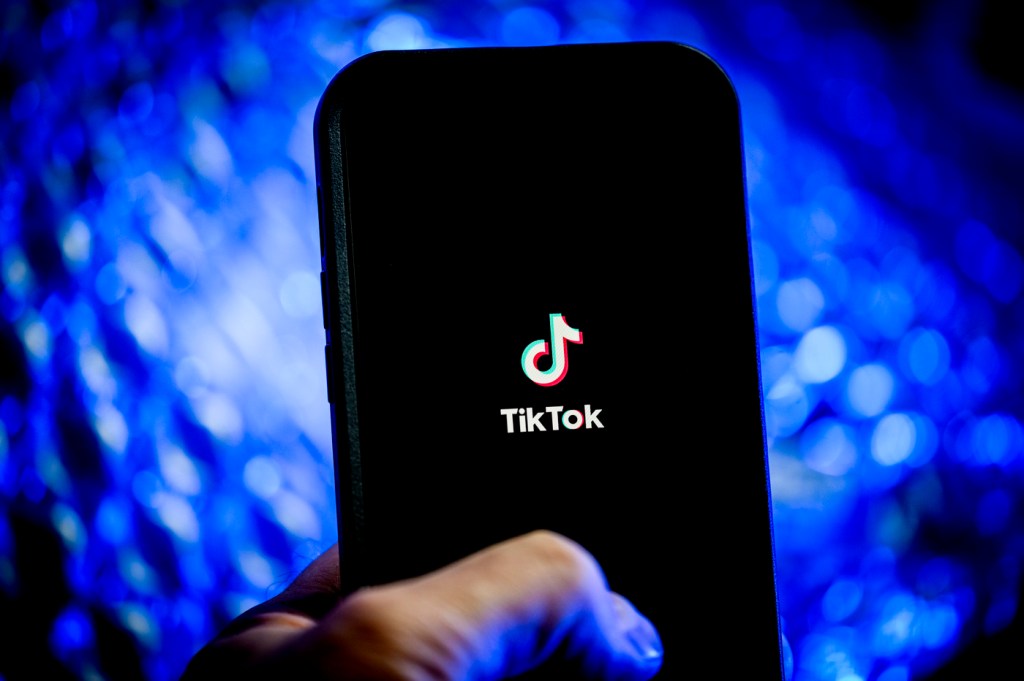Person holding a phone displaying the TikTok app loading screen.