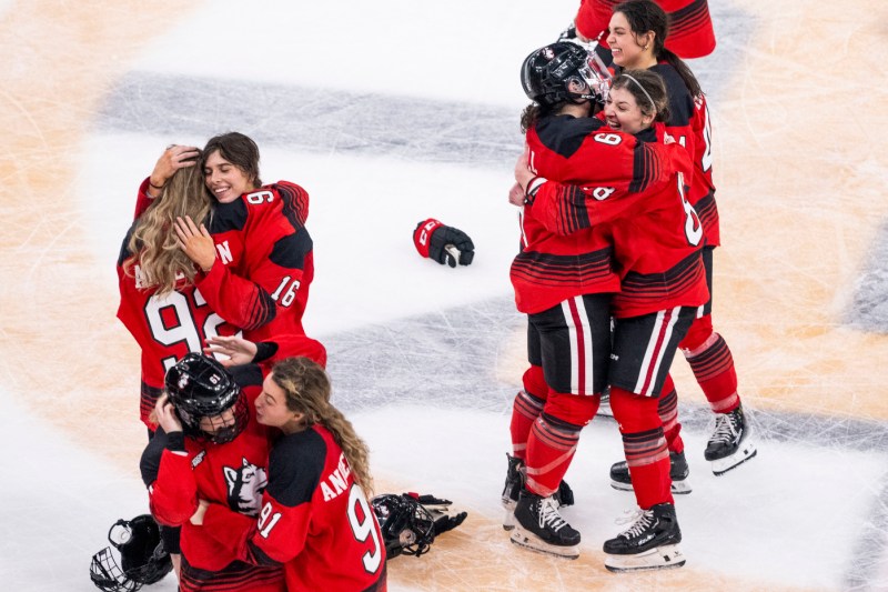 Northeastern women's hockey team members hugging each other on the ice after winning the Beanpot.