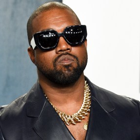 Kanye West at the Oscar Party wearing oversized sunglasses, a black shirt, and a chunky gold necklace.