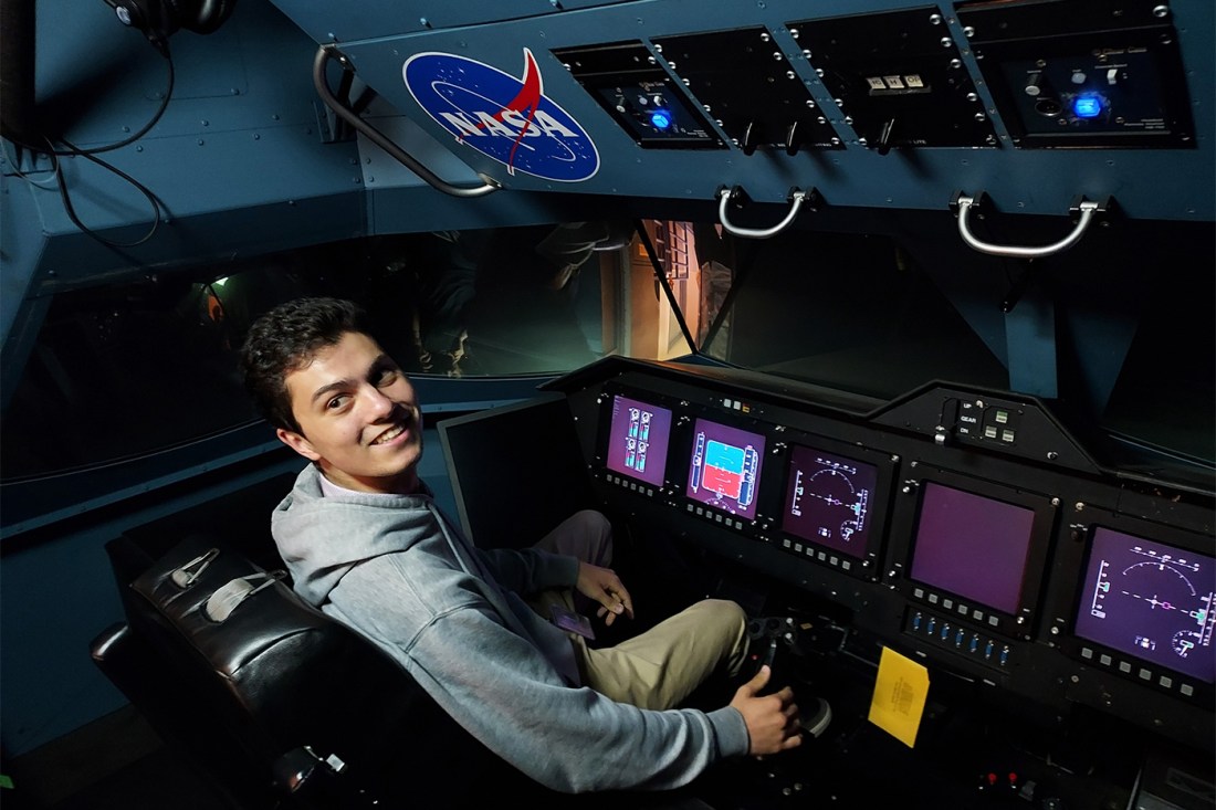 Dillon Nishigaya sitting in the pilot seat of a NASA spacecraft.
