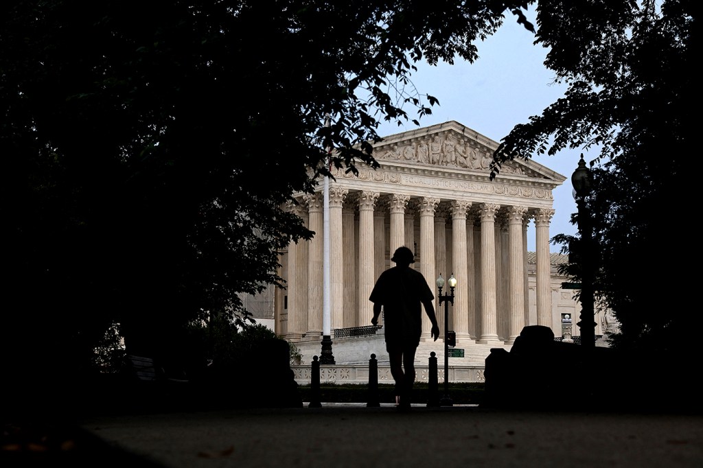 Silhouette of a pedestrian walking in front of the US Supreme Court.