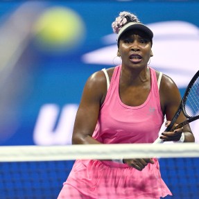 Venus Williams in a matching pink tennis set waiting for the ball to be hit to her.