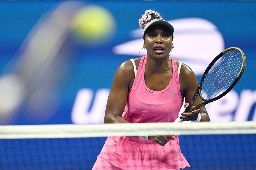 Venus Williams in a matching pink tennis set waiting for the ball to be hit to her.