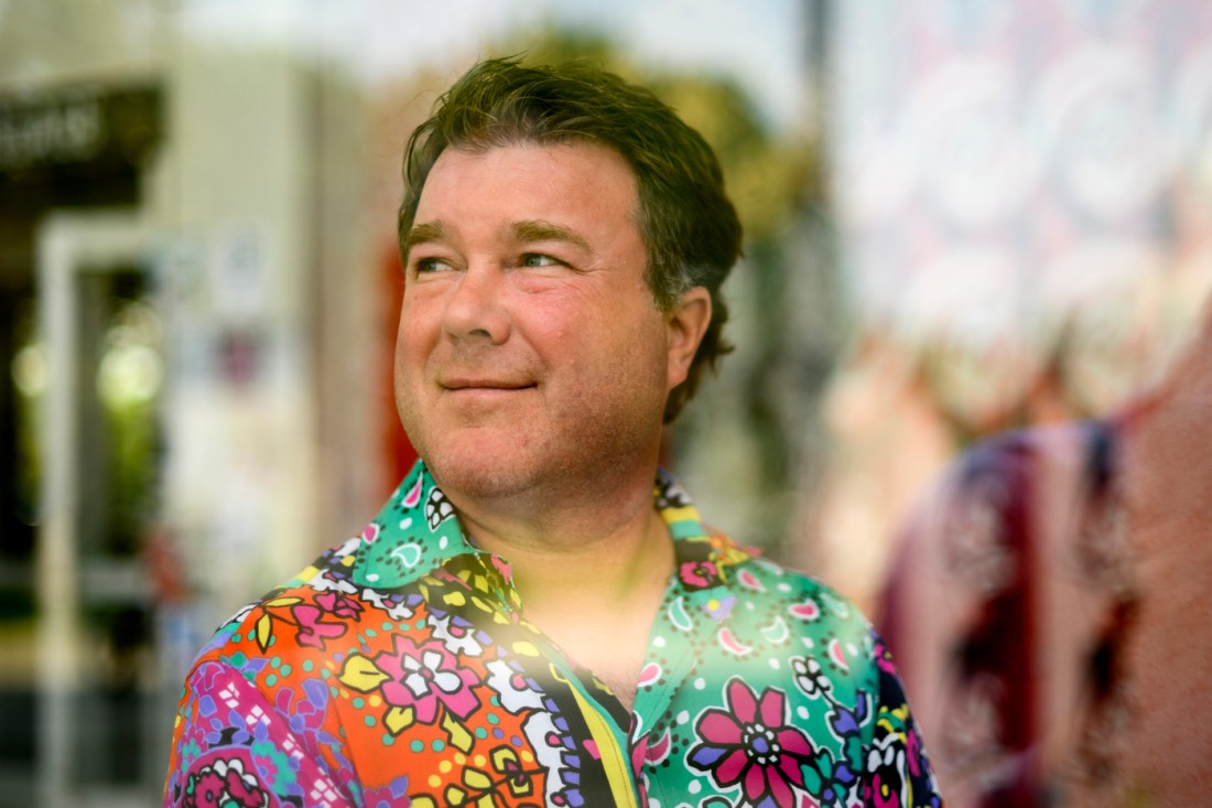 Headshot of Stephen woods wearing a colorful floral printed button down shirt.
