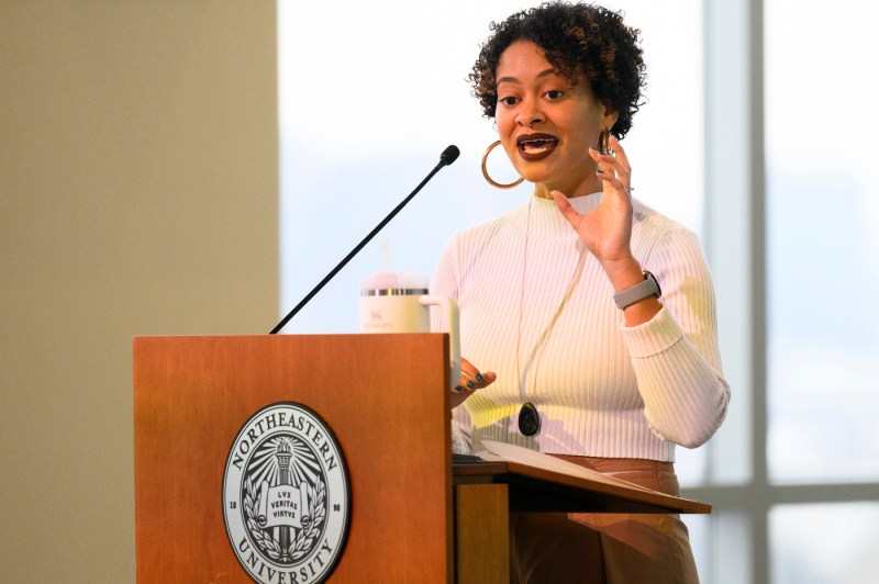 A person wearing a white shirt speaks at a podium at the annual bell hooks symposium.
