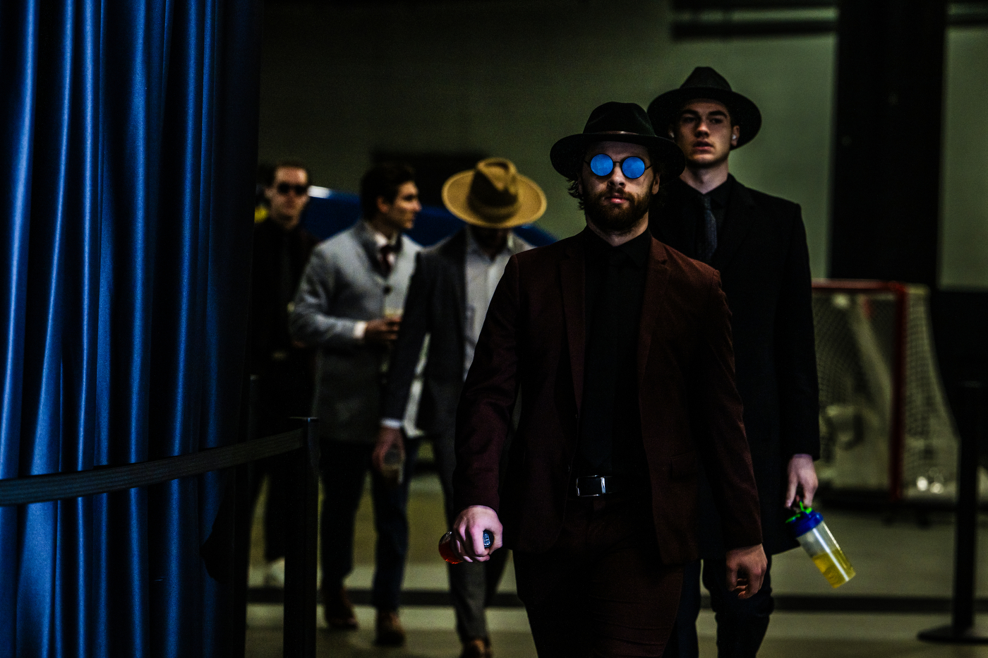 Mens hockey players entering TD Garden in suits and hats.