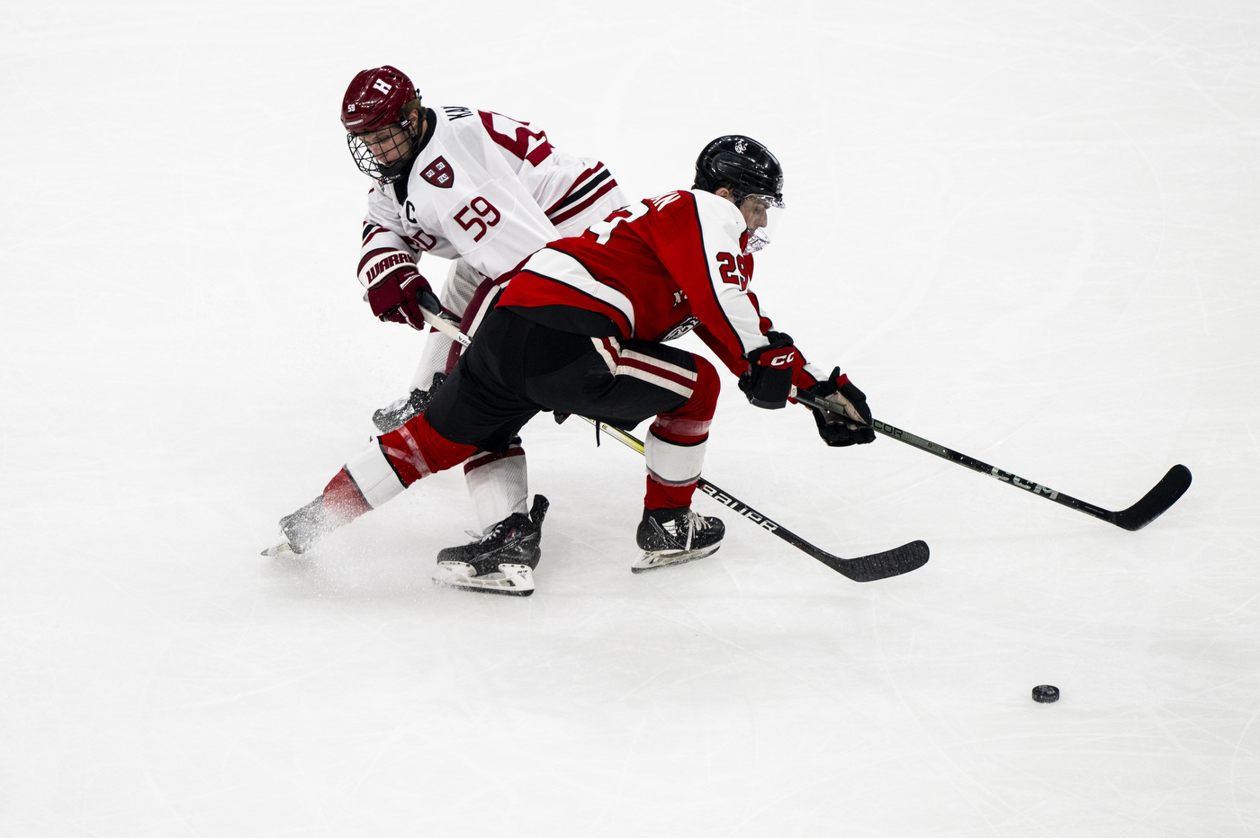 Northeastern hockey player skating past Harvard player with a puck.