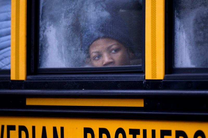 A child looking out the window of a yellow school bus. 