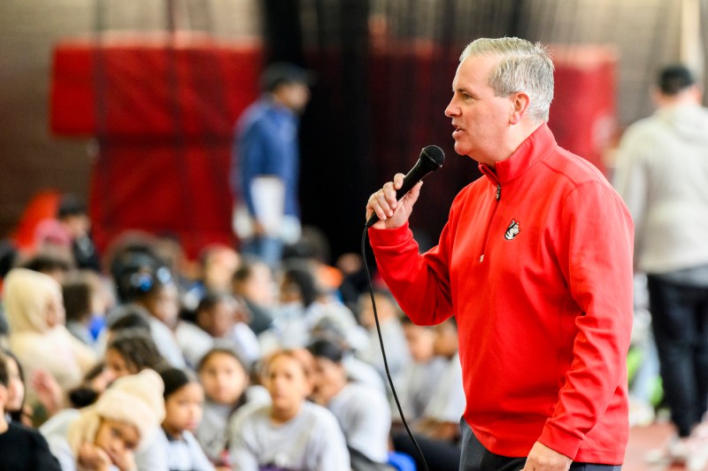 John Tobin wearing a red Northeastern quarter zip speaking into a microphone.