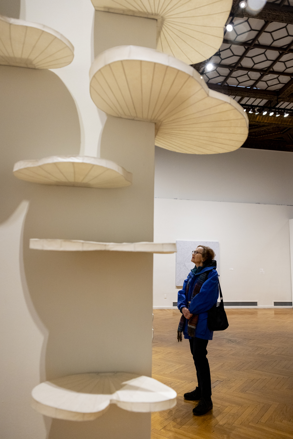 A person looking up at a sculpture in the center of an art gallery.