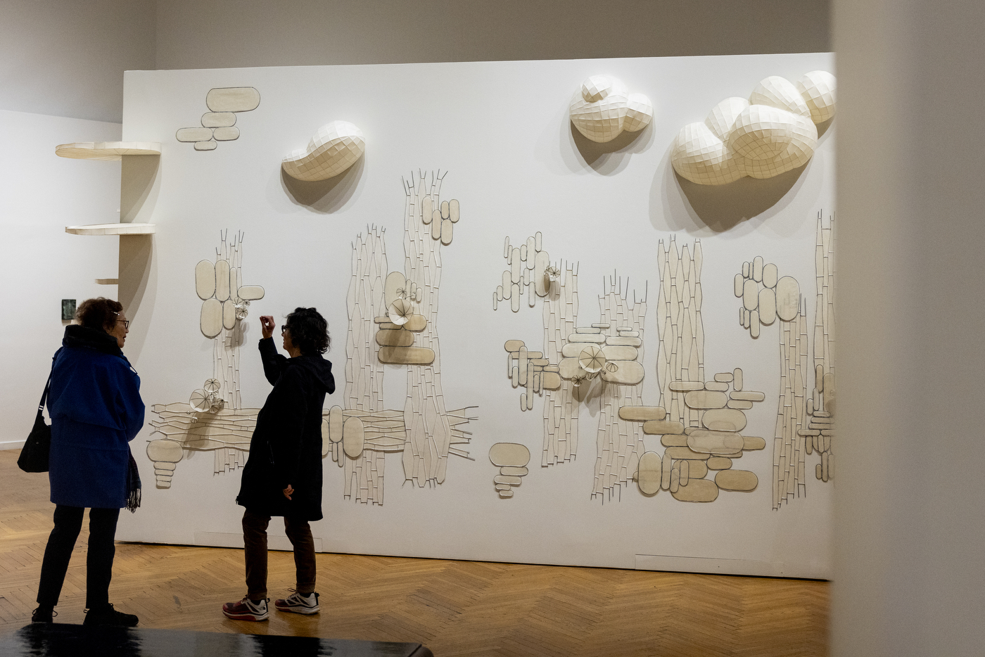 Two people standing in front of a wall sized art display.