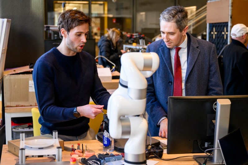 Someone shows a robot in a lab setting to Simon Harris.