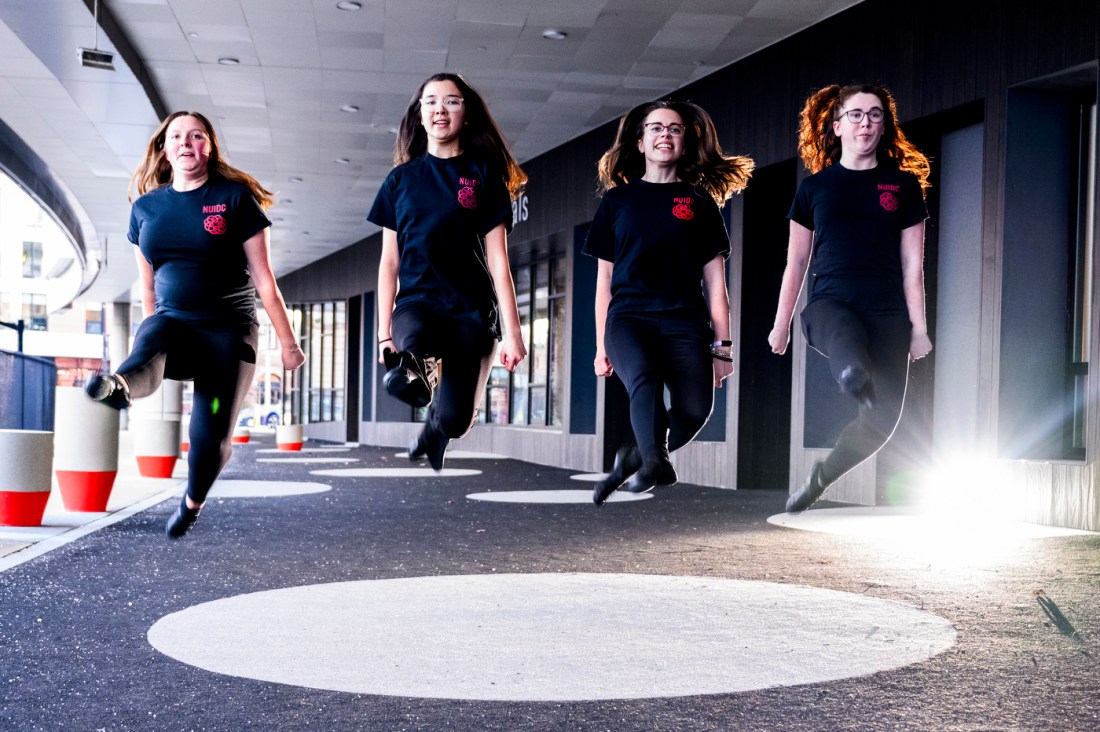 Four Northeastern’s Irish Dance Club members dance together in a line outside.